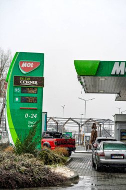 Bir MOL benzin istasyonunun dışı. Benzin pompaları ve arabalar kar yağarken yakıt ikmali yapıyorlar.