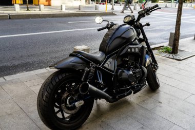 Güneşli bir yaz gününde klasik bir motosiklet caddeye park edilmiş.