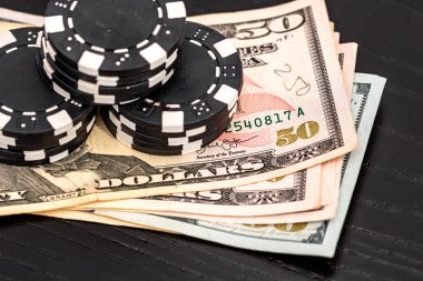 Siyah arka planda parası olan poker fişleri yığını, Amerikan Doları para birimi