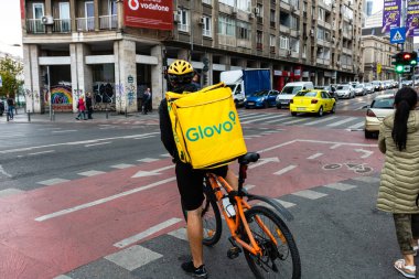 Bisikletli Glovo gıda kuryesi Romanya 'nın Bükreş kentinde yiyecek dağıtıyor