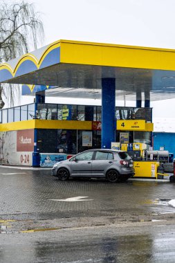 PETROM benzin istasyonunun dışı. Benzin pompaları ve arabalar kar yağarken yakıt ikmali yapıyorlar.