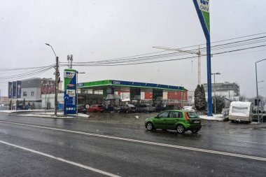 Bir OMV benzin istasyonunun dışı. Benzin pompaları ve arabalar kar yağarken yakıt ikmali yapıyorlar.