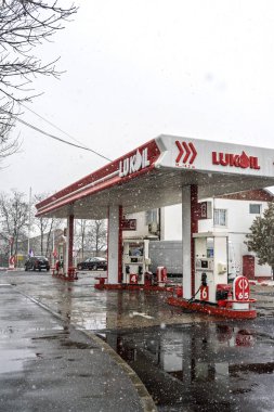 LUKOIL benzin istasyonunun dışı. Benzin pompaları ve arabalar kar yağarken yakıt ikmali yapıyorlar.