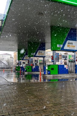 Bir OMV benzin istasyonunun dışı. Benzin pompaları ve arabalar kar yağarken yakıt ikmali yapıyorlar.