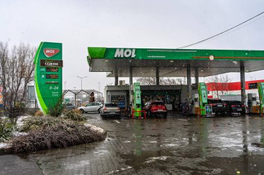 Bir MOL benzin istasyonunun dışı. Benzin pompaları ve arabalar kar yağarken yakıt ikmali yapıyorlar.