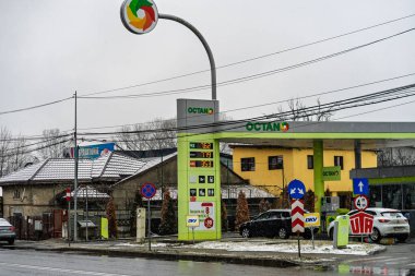 OCTANO benzin istasyonunun dışı. Benzin pompaları ve arabalar kar yağarken yakıt ikmali yapıyorlar.