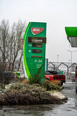 Bir MOL benzin istasyonunun dışı. Benzin pompaları ve arabalar kar yağarken yakıt ikmali yapıyorlar.