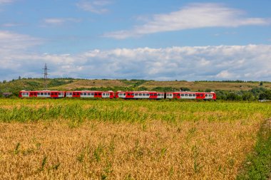 Romanya 'nın kırsal kesiminde bir tren geçiyor. Arazi, Romanya 'nın tipik kırsal kesimlerine özgü buğday ve mısır tarlalarından oluşuyor.