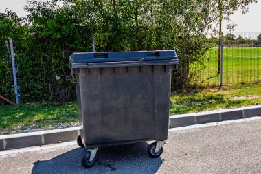 Menteşeli kapaklı polietilen plastikten yapılmış büyük bir çöp kutusu.