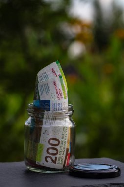 İsviçre frangı CHF banknotu cam kavanozda para biriktiriyor. Tüketim ve ekonomi. İş, bahşiş, finans, tasarruf, bankacılık ve insan kavramı
