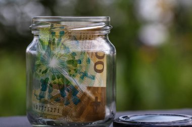 İsviçre frangı CHF banknotu cam kavanozda para biriktiriyor. Tüketim ve ekonomi. İş, bahşiş, finans, tasarruf, bankacılık ve insan kavramı