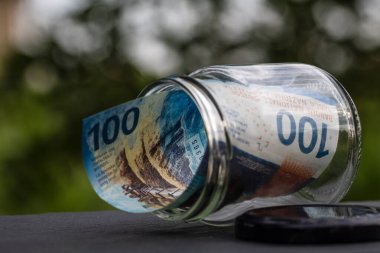 İsviçre frangı CHF banknotu cam kavanozda para biriktiriyor. Tüketim ve ekonomi. İş, bahşiş, finans, tasarruf, bankacılık ve insan kavramı