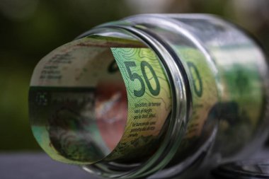İsviçre frangı CHF banknotu cam kavanozda para biriktiriyor. Tüketim ve ekonomi. İş, bahşiş, finans, tasarruf, bankacılık ve insan kavramı