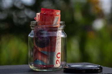 İsviçre frangı CHF banknotu cam kavanozda para biriktiriyor. Tüketim ve ekonomi. İş, bahşiş, finans, tasarruf, bankacılık ve insan kavramı