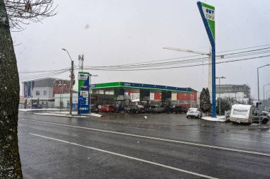 Bir OMV benzin istasyonunun dışı. Benzin pompaları ve arabalar kar yağarken yakıt ikmali yapıyorlar.