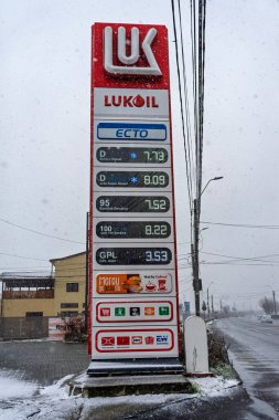 LUKOIL benzin istasyonunun dışı. Benzin pompaları ve arabalar kar yağarken yakıt ikmali yapıyorlar.
