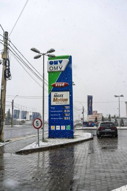 Bir OMV benzin istasyonunun dışı. Benzin pompaları ve arabalar kar yağarken yakıt ikmali yapıyorlar.