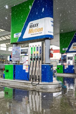 Bir OMV benzin istasyonunun dışı. Benzin pompaları ve arabalar kar yağarken yakıt ikmali yapıyorlar.