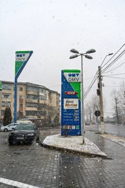 Bir OMV benzin istasyonunun dışı. Benzin pompaları ve arabalar kar yağarken yakıt ikmali yapıyorlar.