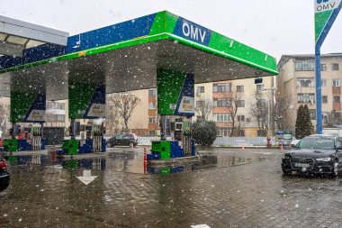 Bir OMV benzin istasyonunun dışı. Benzin pompaları ve arabalar kar yağarken yakıt ikmali yapıyorlar.