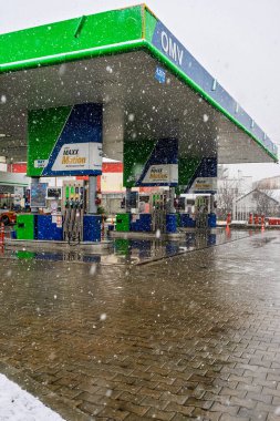 Bir OMV benzin istasyonunun dışı. Benzin pompaları ve arabalar kar yağarken yakıt ikmali yapıyorlar.