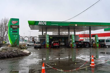 Bir MOL benzin istasyonunun dışı. Benzin pompaları ve arabalar kar yağarken yakıt ikmali yapıyorlar.