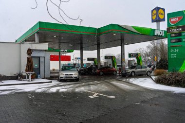 Bir MOL benzin istasyonunun dışı. Benzin pompaları ve arabalar kar yağarken yakıt ikmali yapıyorlar.