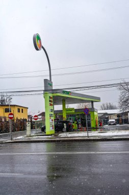 OCTANO benzin istasyonunun dışı. Benzin pompaları ve arabalar kar yağarken yakıt ikmali yapıyorlar.