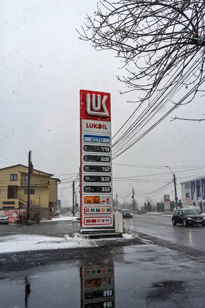 LUKOIL benzin istasyonunun dışı. Benzin pompaları ve arabalar kar yağarken yakıt ikmali yapıyorlar.