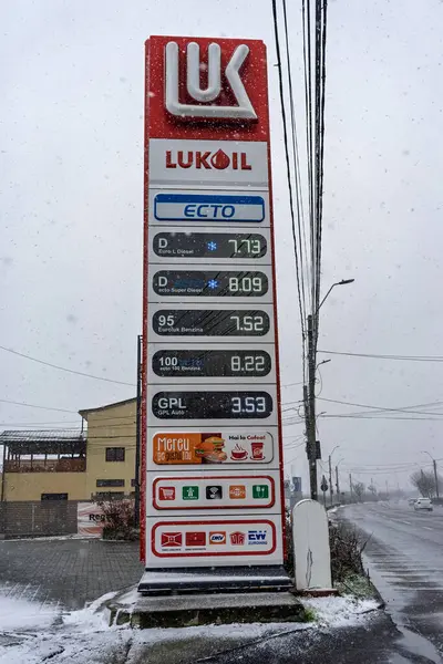 LUKOIL benzin istasyonunun dışı. Benzin pompaları ve arabalar kar yağarken yakıt ikmali yapıyorlar.