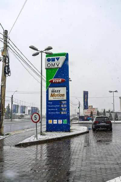 Bir OMV benzin istasyonunun dışı. Benzin pompaları ve arabalar kar yağarken yakıt ikmali yapıyorlar.