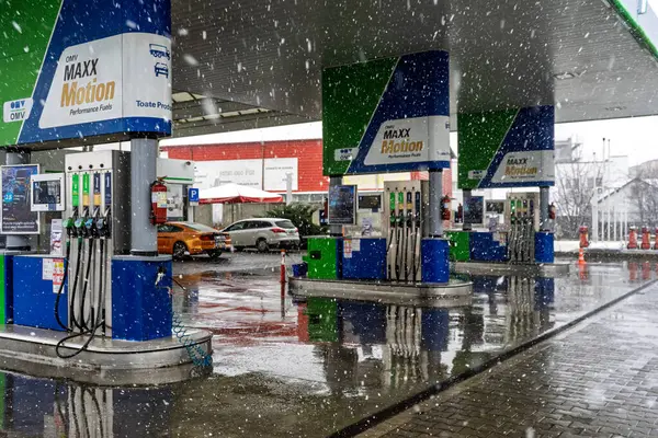 Bir OMV benzin istasyonunun dışı. Benzin pompaları ve arabalar kar yağarken yakıt ikmali yapıyorlar.
