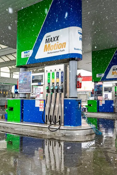 Bir OMV benzin istasyonunun dışı. Benzin pompaları ve arabalar kar yağarken yakıt ikmali yapıyorlar.
