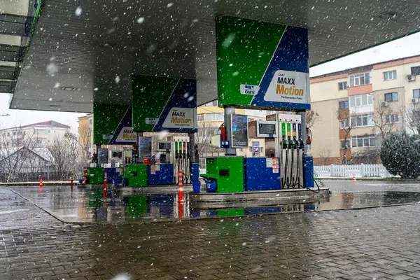 Bir OMV benzin istasyonunun dışı. Benzin pompaları ve arabalar kar yağarken yakıt ikmali yapıyorlar.