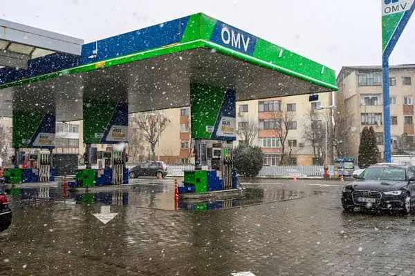Bir OMV benzin istasyonunun dışı. Benzin pompaları ve arabalar kar yağarken yakıt ikmali yapıyorlar.