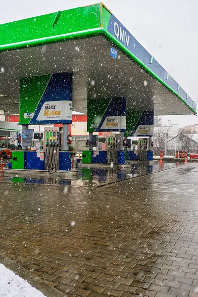 Bir OMV benzin istasyonunun dışı. Benzin pompaları ve arabalar kar yağarken yakıt ikmali yapıyorlar.