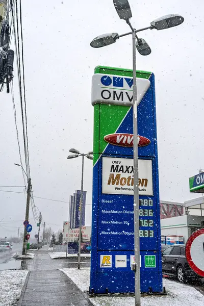 Bir OMV benzin istasyonunun dışı. Benzin pompaları ve arabalar kar yağarken yakıt ikmali yapıyorlar.