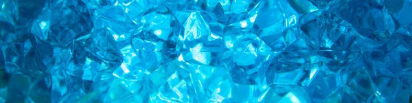Bright blue crystals made of glass look like gems close-up in the blur. Background from blue stones crystals. Close-up.