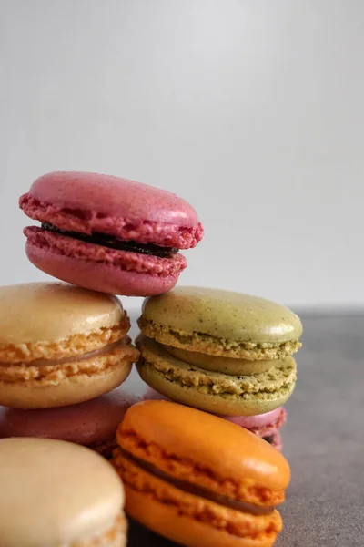 A pile of colorful sweet French macarons against a neutral background.