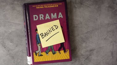 Raina Telgemeier 'in çizgi romanı Drama' nın bir kopyası. Kitap, okul ve kütüphanelerdeki pek çok yasaklı kitap listesine girdi..