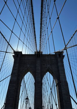 Brooklyn Köprüsü 'ndeki bir kuleye giden kablolar mavi gökyüzüne karşı.