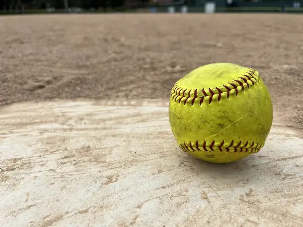 Ground level view of a softball on home plate.