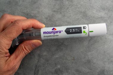 Mounjaro iğneli kalemi tutan el.