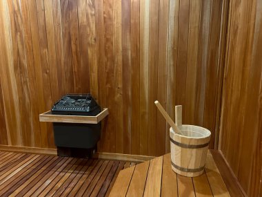 Kaplıcadaki saunanın içinde, kuru odada nem yaratmak için su kovası ve sauna taşlarını gösteriyor..