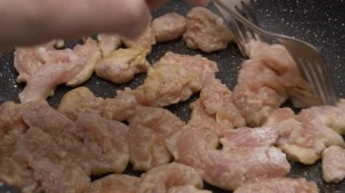 Bir aşçı çatallı tavada tavuk etini birbirinden ayırıyor. 