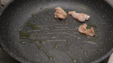 Bir aşçı içinde sıcak yağ olan tavaya küçük tavuk eti parçaları ekliyor. Yüksek kalite 4k görüntü