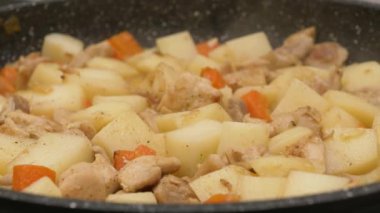 Patates ve havuçlu küçük tavuk filetosu parçaları, düşük ısıda bir tencerede kaynıyor. Güveçten buhar yükseliyor. Yüksek kalite 4k görüntü