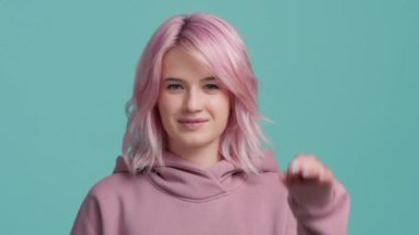 Neşeli, komik hippi 20 'li yaşlarda, moda pembe saçlı, kameraya dil gösteren, parmaklarıyla şarkı söyleyen, şakalaşan, şakalaşan bir kız. Genç ve güzel bir kız stüdyo geçmişi var.