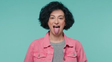 40 'lı yaşlarda pembe kot ceketli neşeli ve olgun bir kadın kameraya dil gösteriyor, şakalaşıyor. Yavaş çekim 4K ile izole edilmiş stüdyo arka planında güzel bir kadın model.
