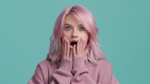 ショックを受けたピンクの髪をした怖がって若い女性の肖像画を閉じると 驚きと不思議の広い口を開けて顔に触れる ピンクの髪のヒップスターモデルスローモーションスタジオショット緑青の背景 — ストック動画